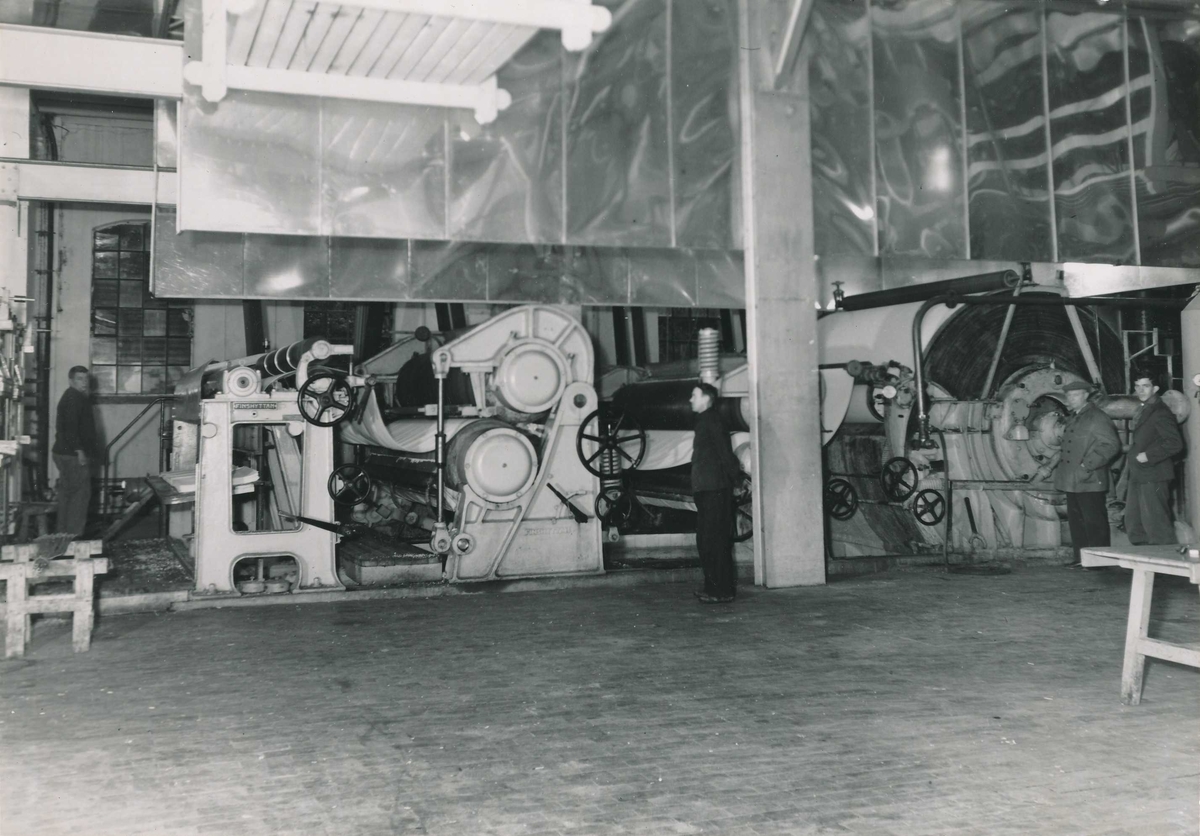 Fire menn ved oppfangermaskinen i produksjonssalen i det gamle tremsliperiet.