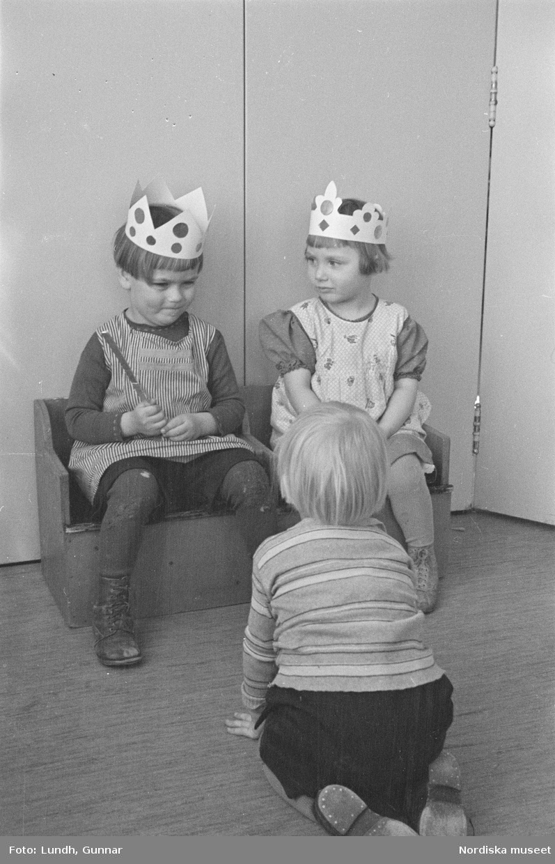 Motiv: H.S.B.s lekstuga på Skeppargat. (gärdet) (Skeppargatan) (HSB);
Ett barn leker i en leksaksbåt, barn leker med dockservis och dockor, två barn har kronor av papper, två barn kramas.