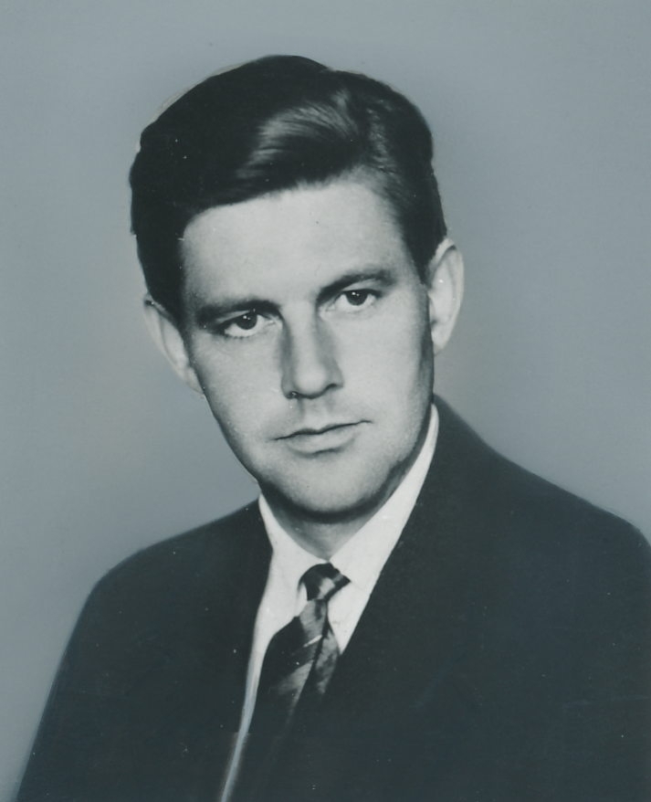 Portrett av mann i 30-årsalderen, iført dressjakke, skjorte og slips.
