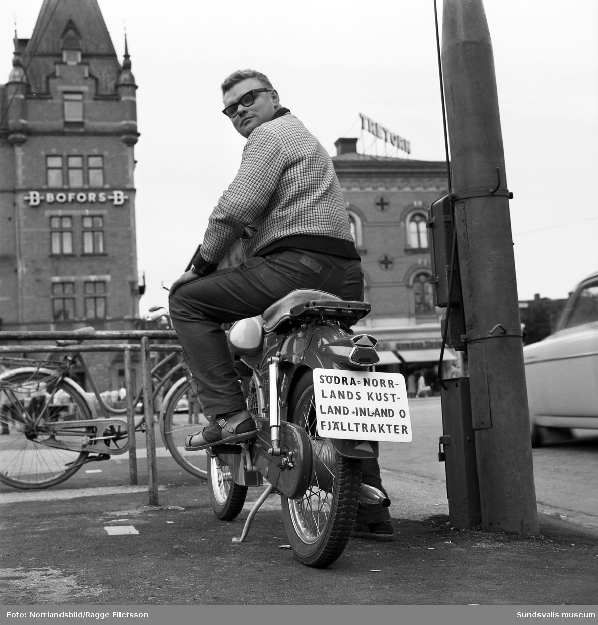 Lennart Berg på torget med sin moped med skylten: "Södra Norrlands kustland inland o fjälltrakter"