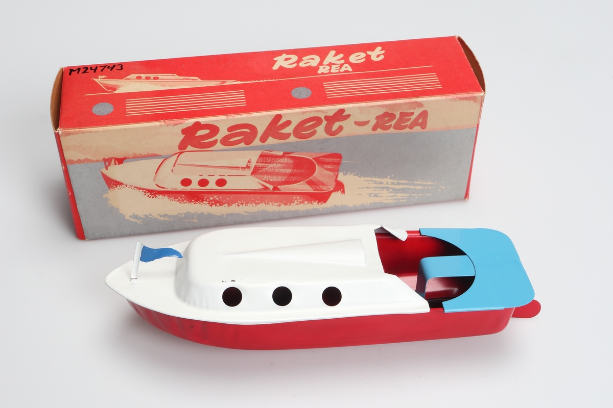 Båt (leksak) tillverkad av lackerad plåt i färgerna blått, rött och vitt. Framdrives genom upphettning av ett membran, eldas med s.k. "Metatabletter". Båten går framåt i vattnet av den s.k. "Reaprincipen". Förvaras i originalförpackning.

Inskrivet i huvudkatalog 1980.