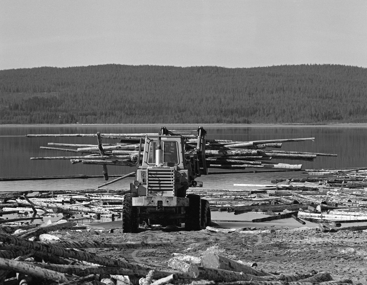 Hjullaster løfter ut i vannet ved Osmundsand ved Osensjøen i Nordre Osen, Åmot kommune, Hedmark våren 1984. Dette ble den siste sesongen det ble fløtet tømmer på denne innsjøen. Fløtinga i tilløpselva Nordre Osa, som har sitt utløp ved Osmund hadde opphørt 14-15 år tidligere, men mye tømmer fra dette området ble kjørt til Nordre Osen med lastebiler og lesset av på land på dette stedet. Etter at tømmerveltene var skjøvet ut i vannet, ble løstømmeret samlet i bommer, som ble buksert mot Valmen og elva Søndre Osas utløp fra sjøen, som ligger på vestsida. I 1984  var det 13 212 kubikkmeter som ble fløtet fra Osensjøen via Søndre Osa og Rena mot Glomma.