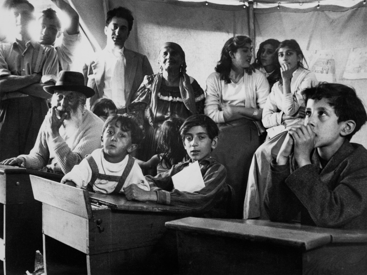 Sommarskola i lägret för romska barn 1957. I bänkarna sitter både vuxna och barn.
