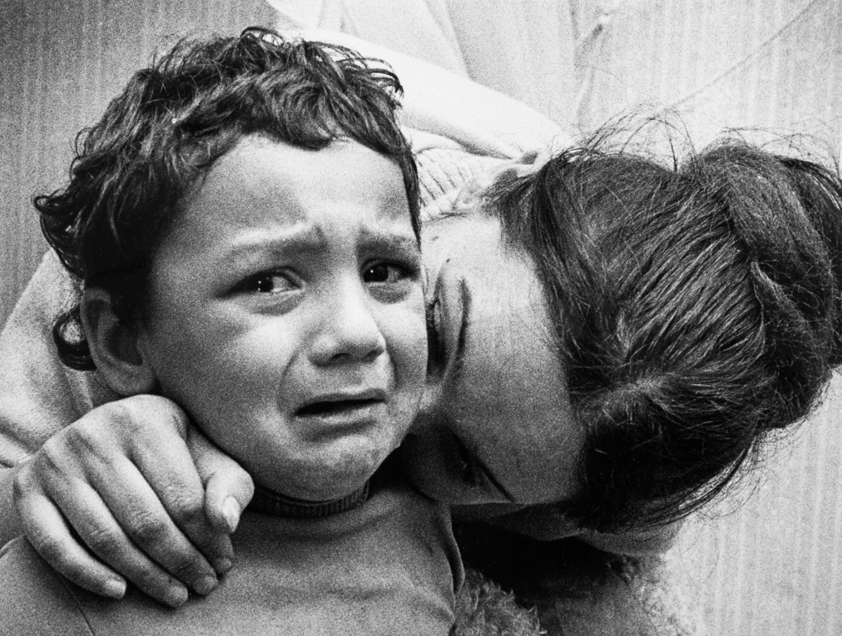 En gråtande pojke tröstas av sin mamma.