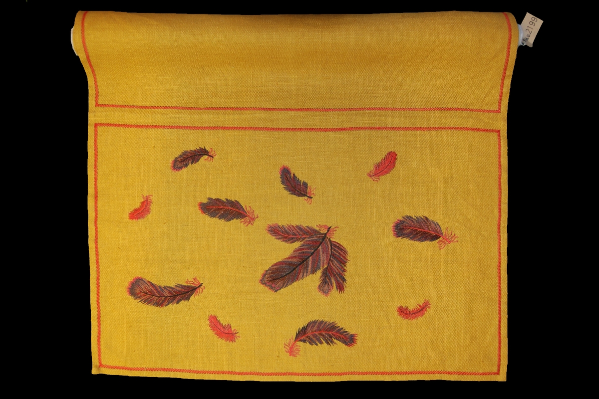 Kudde med baksida, 65 x 41 cm, "Fjädrar". På gul lärft broderi med schattérsöm i merceriserat garn i flera nyanser, brunrött, samt blått och rött, något bomull.