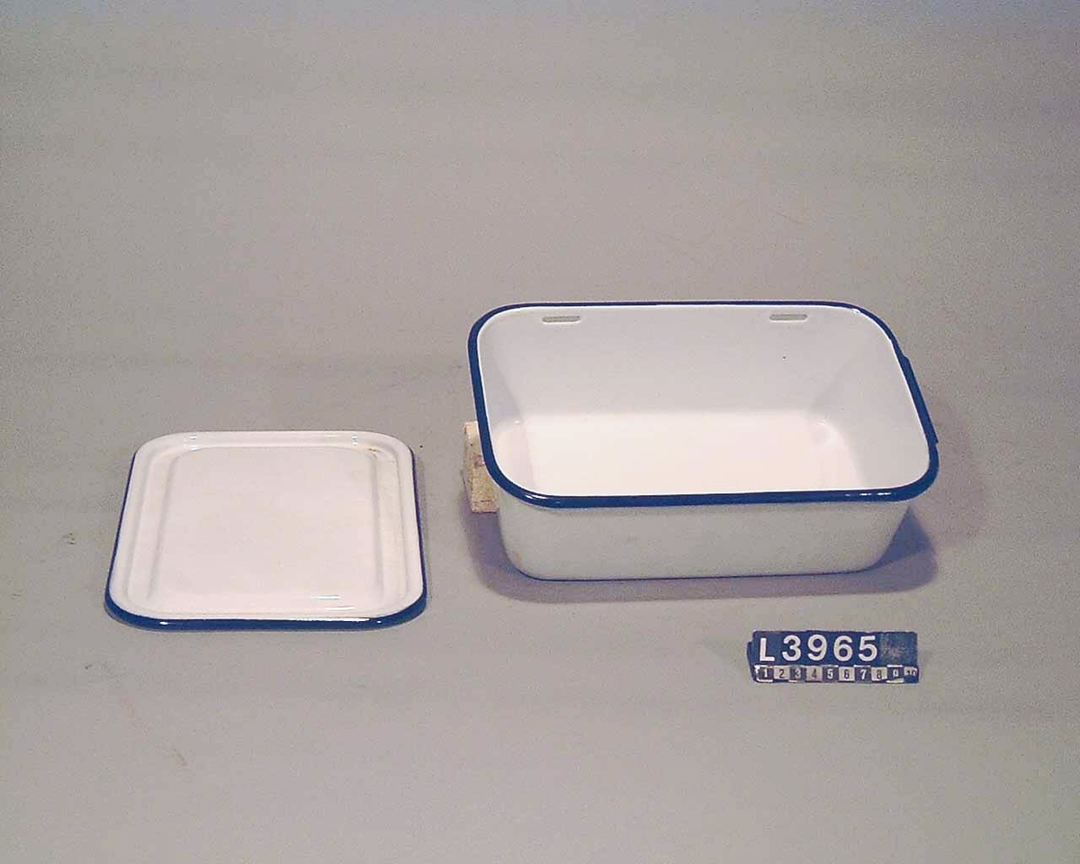 Vitemaljerad låda med blåa kanter och lock för matförvaring. Lådan har ett mått på  35 x 12 cm.