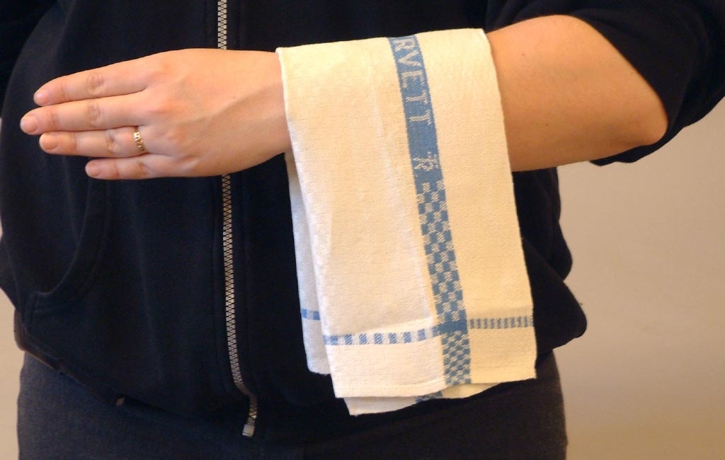 Handduk eller handservett i vitt linne med en vävd blå bård med texten "TR handservett TR" invävt i tyget.