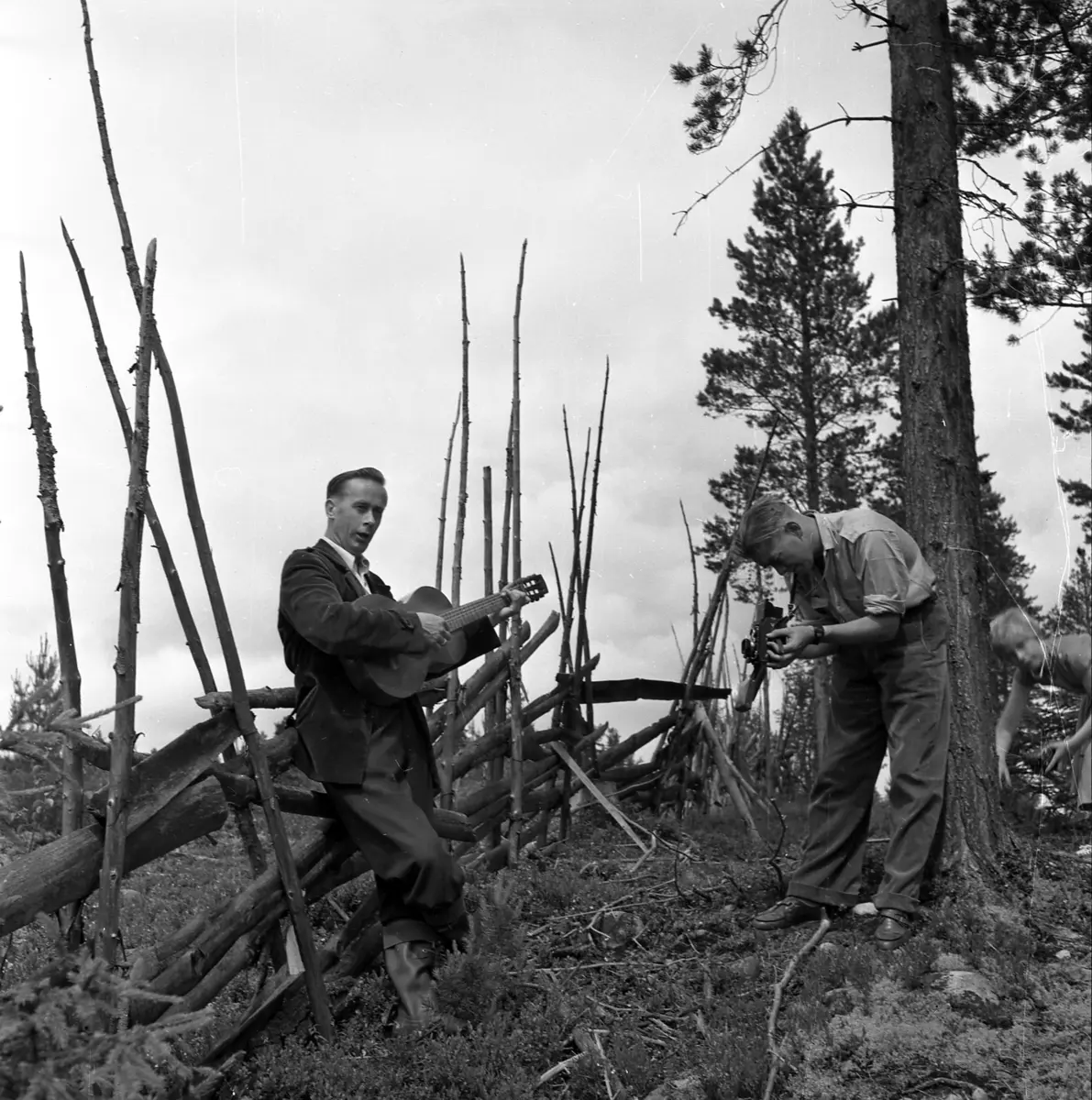 Vidar Sandbeck blir filmet mens han spiller gitar. De er ute og Vidar står lent mot en skigard