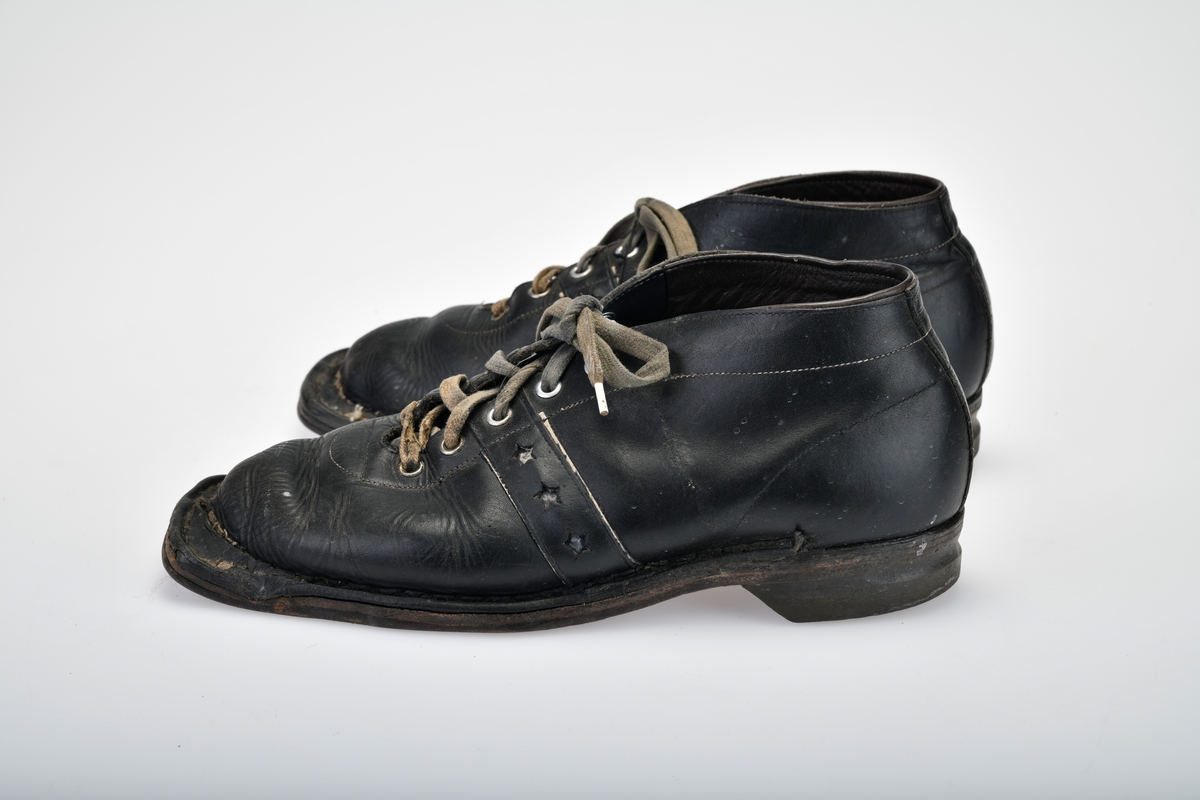 Et par beksømstøvler i størrelse 42 brukt som skisko og tursko. Skoene har randsydde lærsåler og gummihæler. Foran er de firkantet for feste i skibinding, og på undersiden er det tre hull til feste i skibinding. Det er skrudd på slitejern ved hullene. Bak på hælen er det spor til kandaharbinding. I front har skoene 5 par maljer for å snøre skolissene i. Skolissene er grå (opprinnelig hvite) bomullslissser med dekor i hvitt og rødt. Skoene har tunge under snøringen. På hver side av skoen er det skåret ut tre stjerner som dekor.