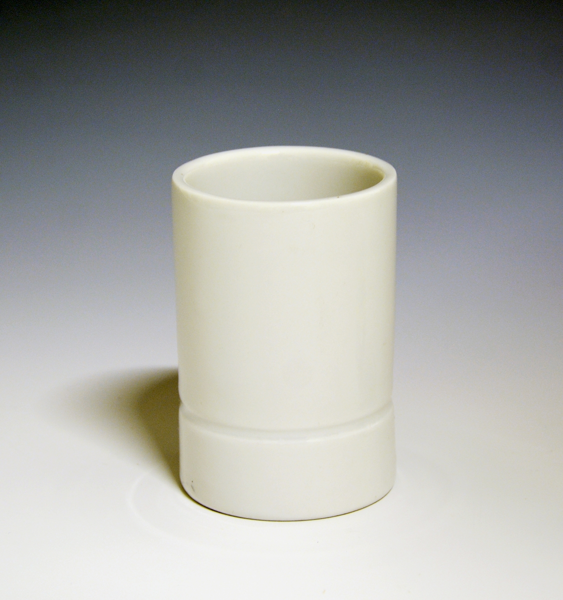 Vase og telysholder av porselen. Fungerer som lysestake den ene veien og vase den andre veien. Sylinderformet med en inntrapping i overgangen mellom vase og telysholder. Hvit glasur. 
Design: Grete Rønning.