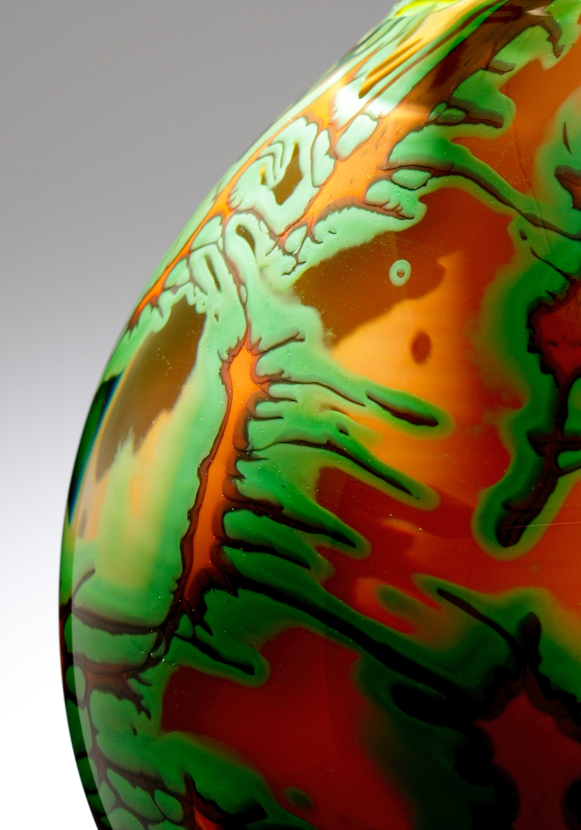 Dubbel-graal av Helen Krantz, i form av en kalebassformad vas med oregelbundet mönster i grönt och orange. Dubbel-graal innebär att det är mönster i dubbla lager. Konstnären och formgivaren är Helen Krantz.