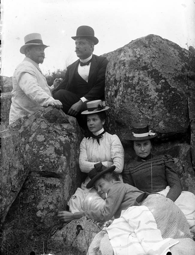 Tre kvinnor och två män poserar vid en sten, ca 1910.