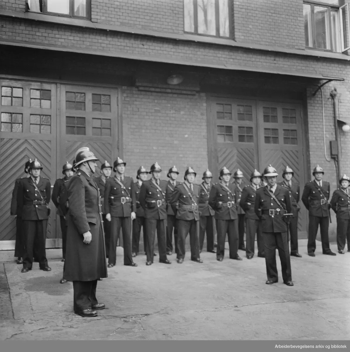 Brannkonstabler paraderer for avtroppende brannmester Sigvald Voldsæter ved Solli brannstasjon i Oslo. Desember 1958.