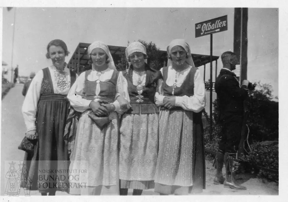 Klara Semb i aust-telemarksbunad, tri kvinner kledde i bunad, med kvitt skaut. Ein bunadkledd mann. Dei står framom eit skilt til Ølbollen.