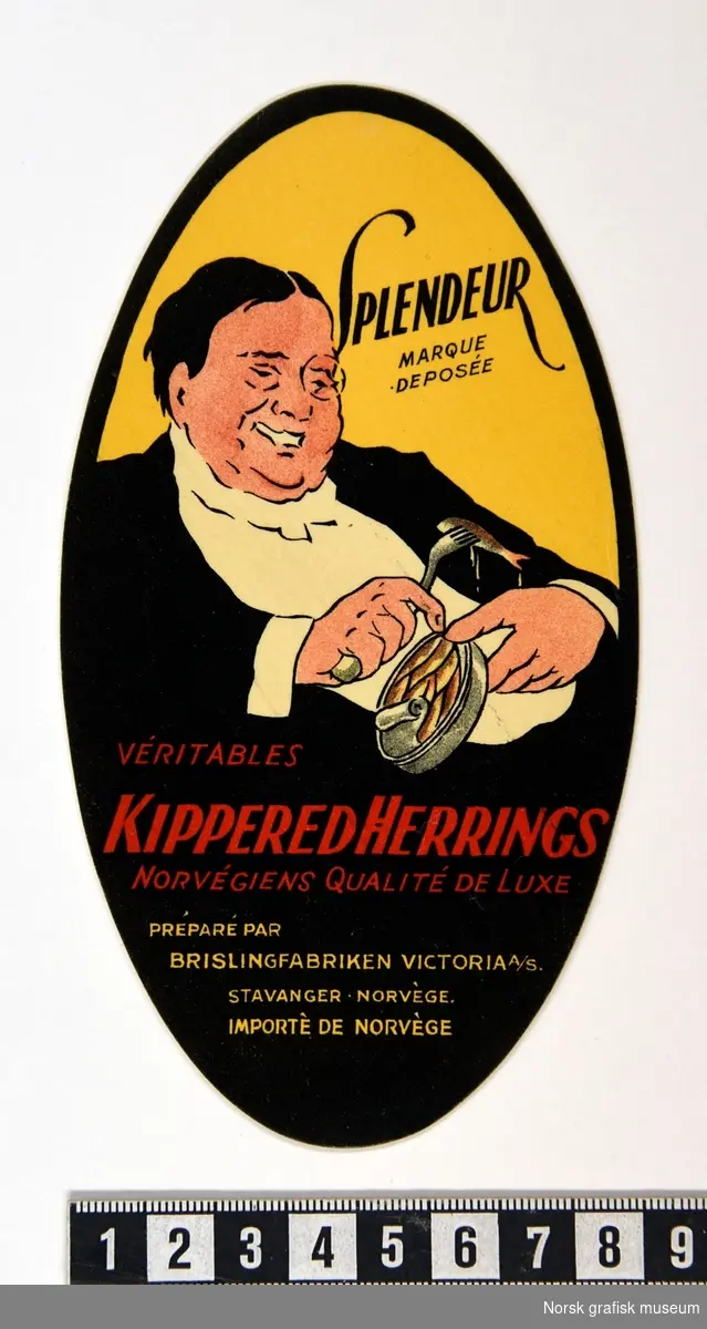 Oval etikett med en illustrasjon av en smilende mann med en åpnet hermetikkboks i den ene hånden, og gaffel med en fisk i den andre hånden. 

"Véritables kippered herrings Norvégiens qualité de luxe"