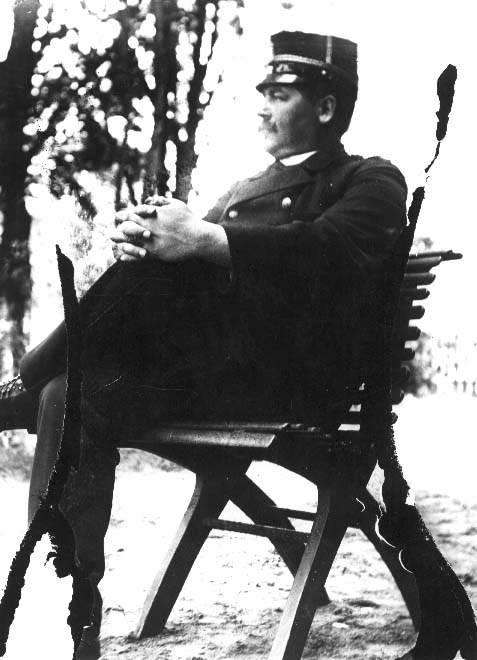 Viktor Lindholmer sitter på en trädgårdsstol men en benet över det andra och händera knäppta över knät. Han bär regementsläkares uniform (Jönköpings regemente).