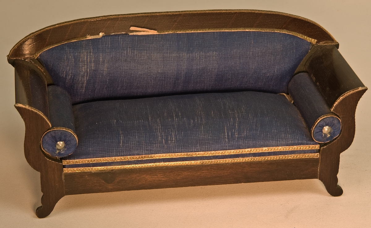 Soffa. Avlång. Karl-Johanstil, med blå sidenklädsel. Karmarna av trä. S-formade. Övre delen av ryggstödet av trä, lätt bågformat.
L 14cm, B 5,5cm, H 4m (sits), H 7cm (ryggstöd).