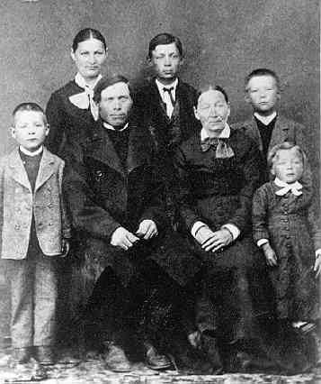 Gruppbild med familjen Anders Johan Andersson i Tuggarp, Gränna socken. Föräldrarna sitter intill varandra på stolar omgivna av fem barn varav en ung kvinna.