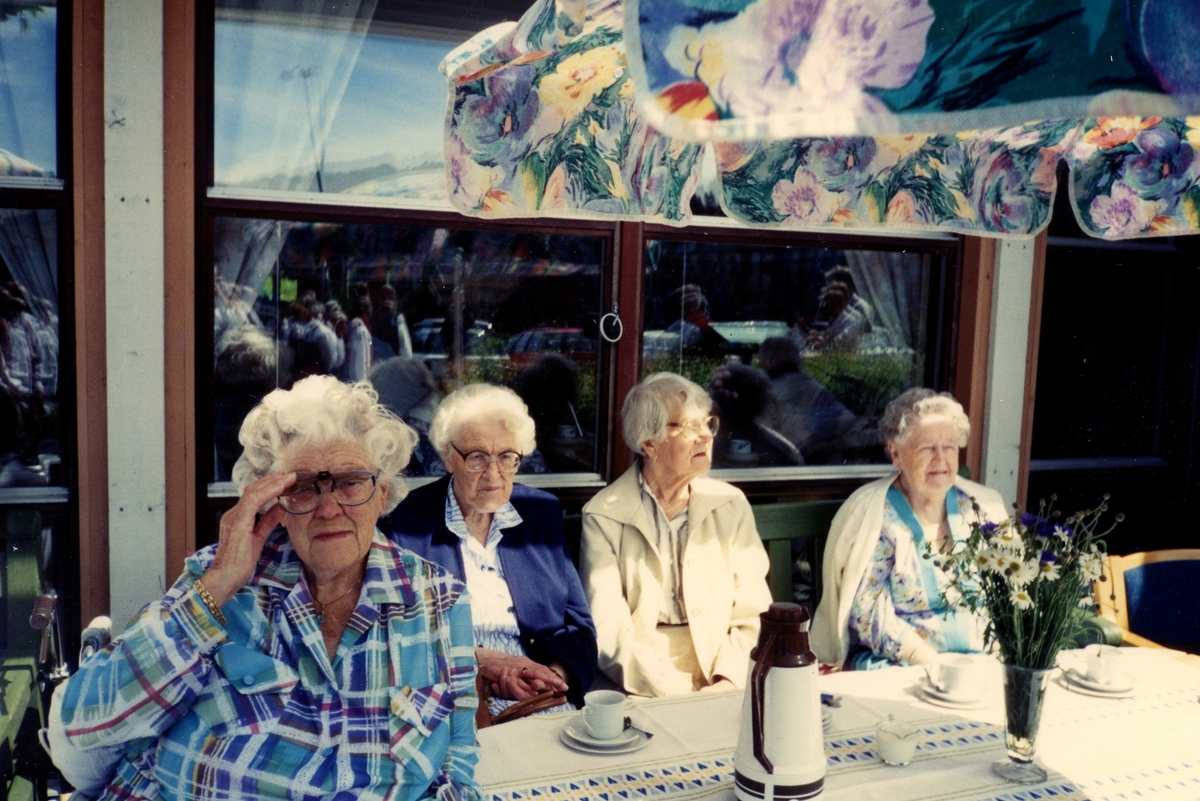 Fyra kvinnor sitter och fikar i solen utanför Brattåsgården (Streteredsvägen 5), cirka 1990. Från vänster: Daga Ahlander (1905 - 1996), Rut Göransson (1905 - 1999), Edit Bernhardsson (1911 - 2000) samt Agnes Eliasson (1904 - 2002).