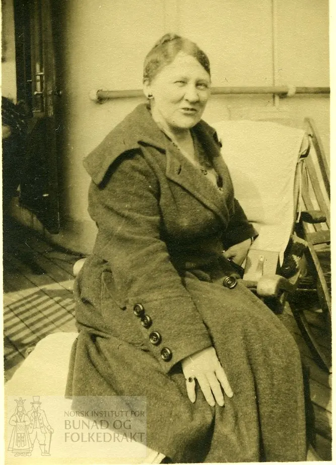 Kvinne i kåpe, sitter på en dekkstol (skip)