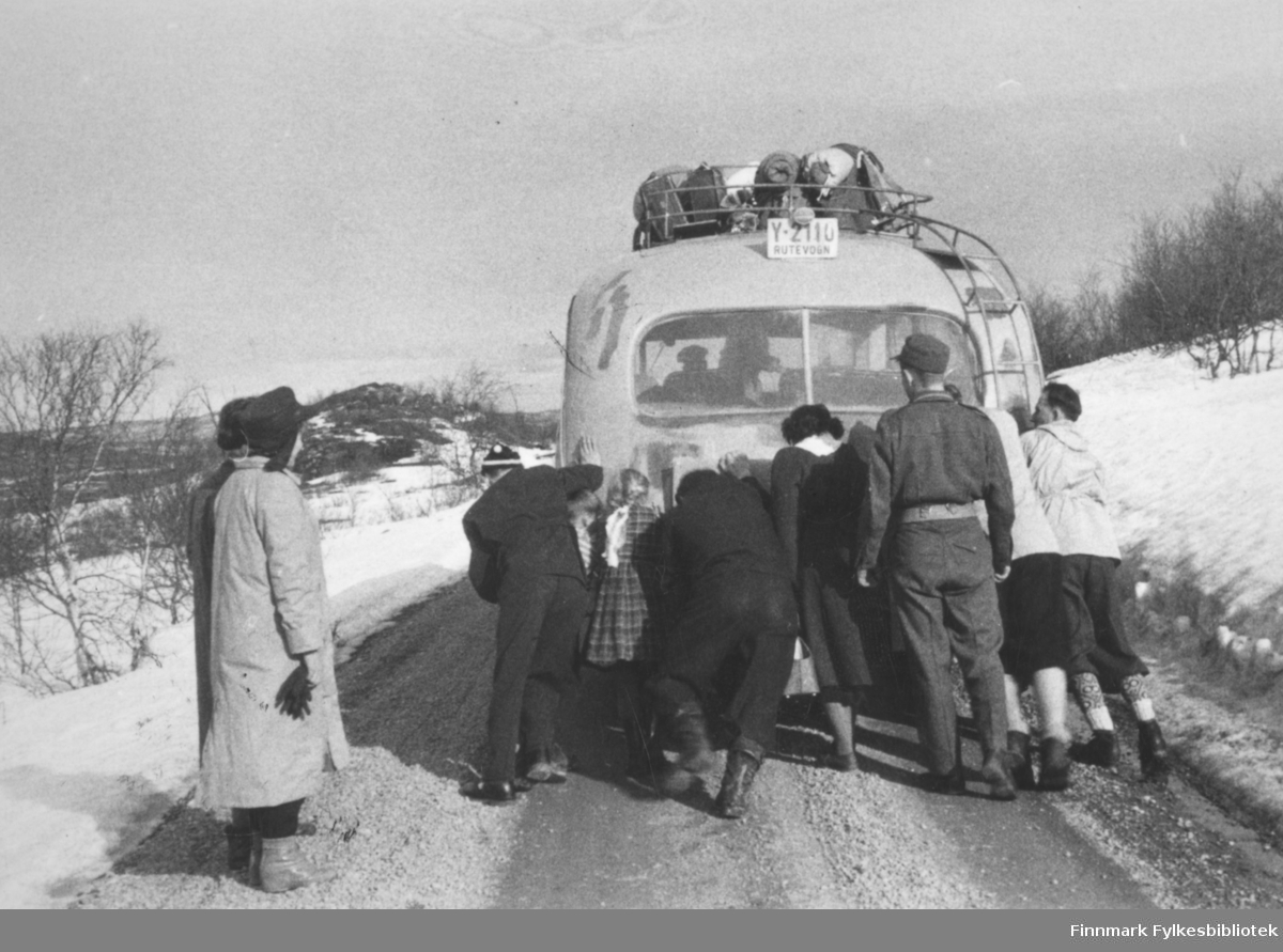 Polarbil-buss med problemer, passasjerene skyver på. Stedet er i nærheten av Skiippagurra, tidspunktet påsken 1956.