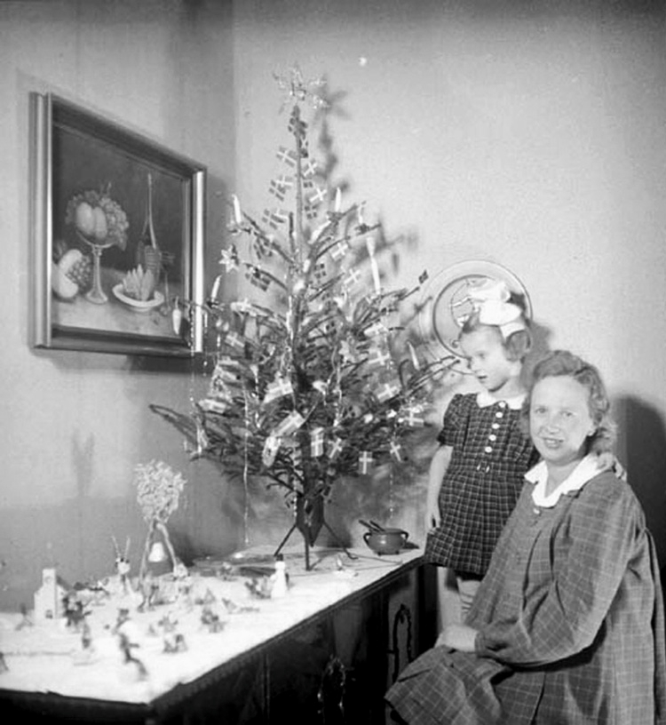 Mor och dotter har pyntat inför julen. Den lilla bordsgranen är klädd med levande ljus, svenska flaggor och en glitterstjärna i toppen.