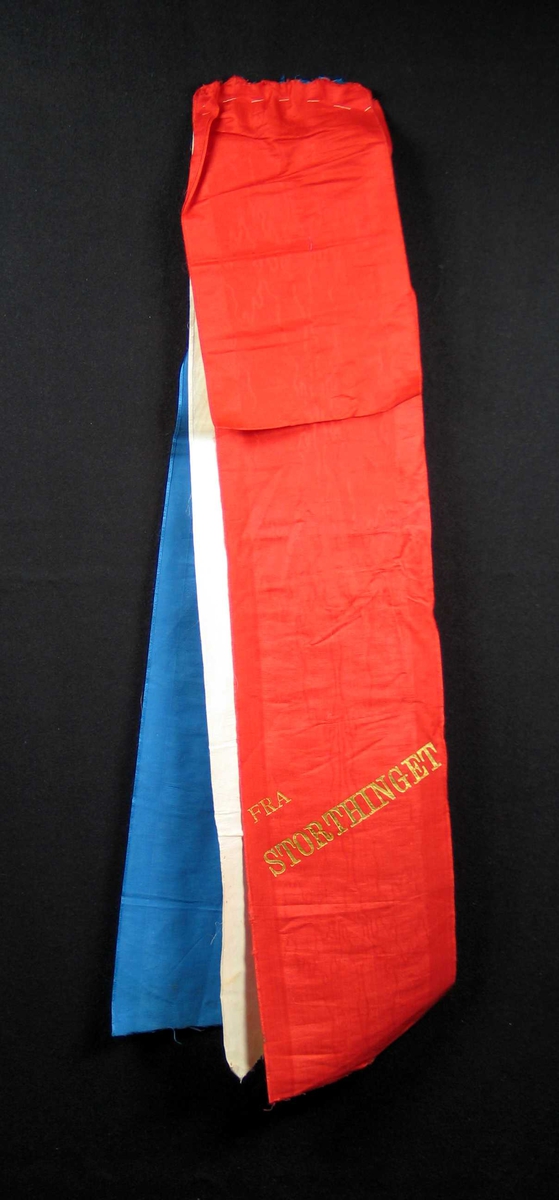 Begravelsessløyfe i rød, hvit og blå silke med tekst i gull.