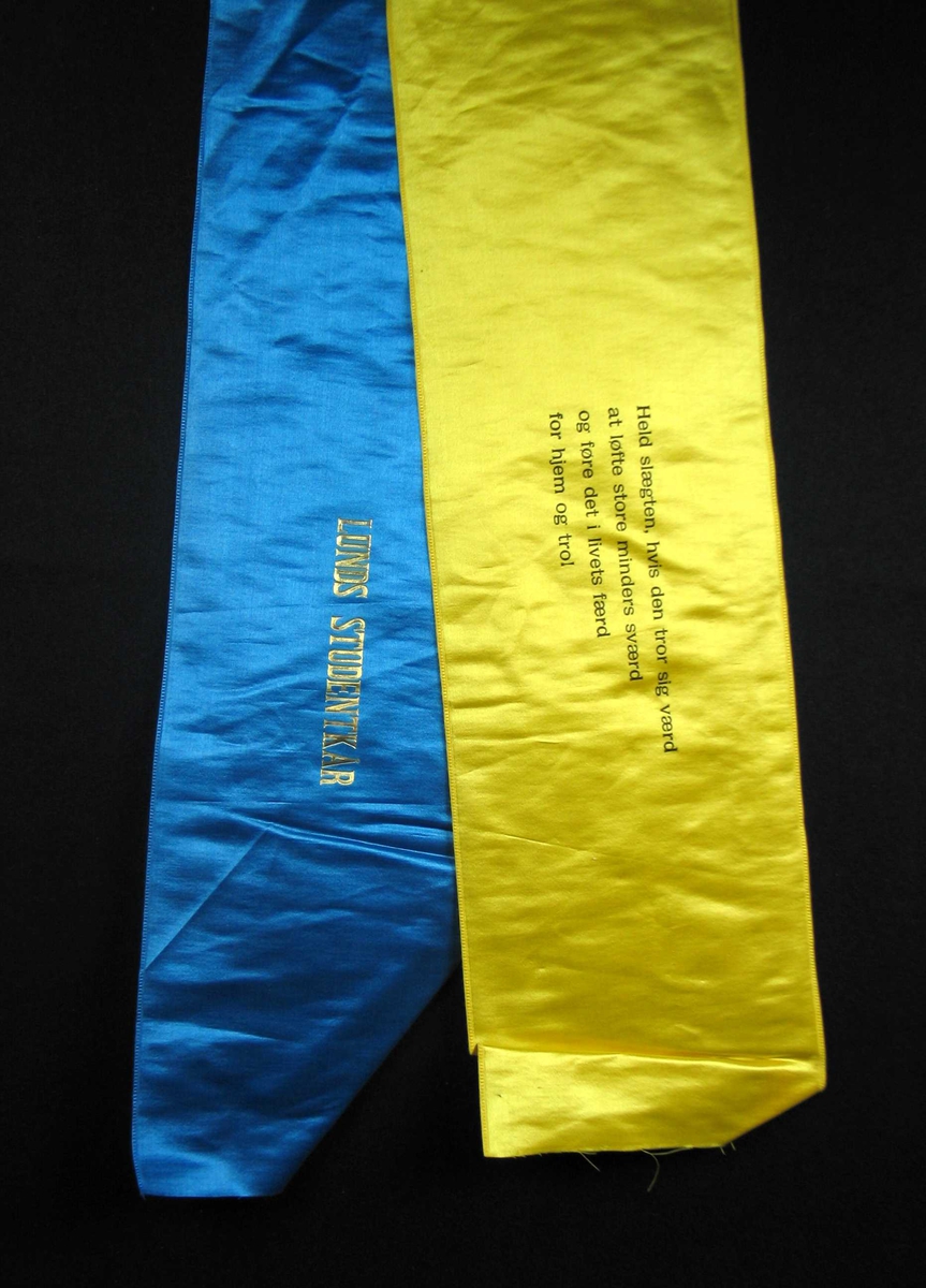 Begravelsessløyfe i blå og gul silke med tekst i svart og gull.