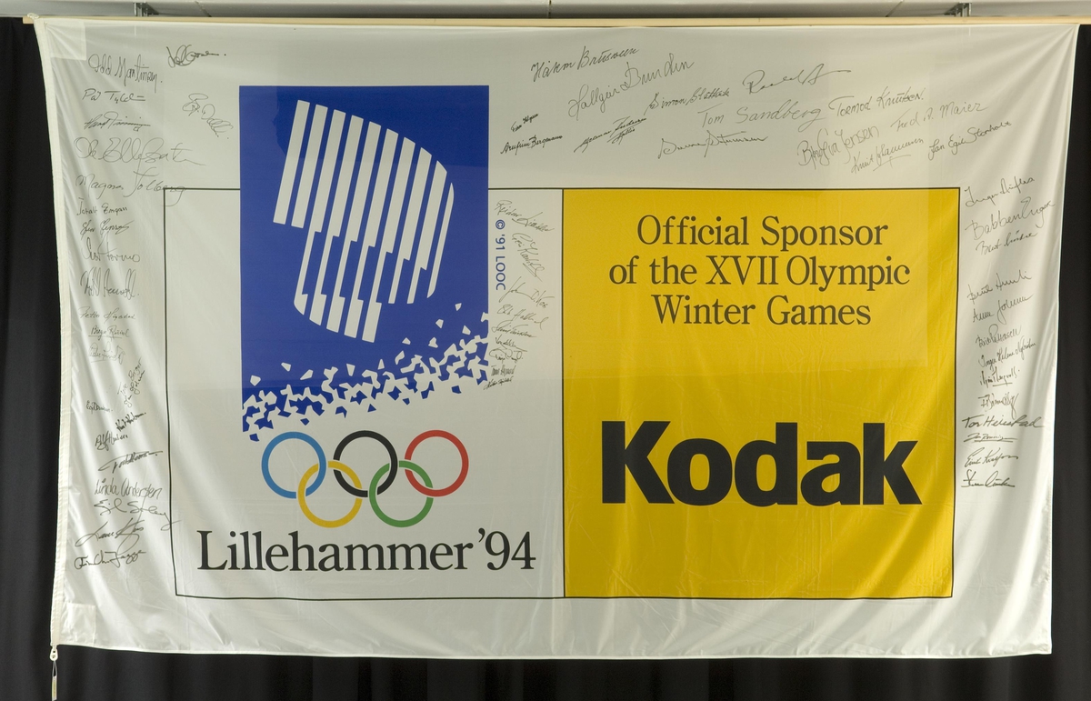 Banner med logo for Kodak og de olympiske vinterleker på Lillehammer i 1994. Hovedfargen hvit. Banneret har ca. 60 signaturer av tidligere og nåværende medlemmer av Gullklubben.