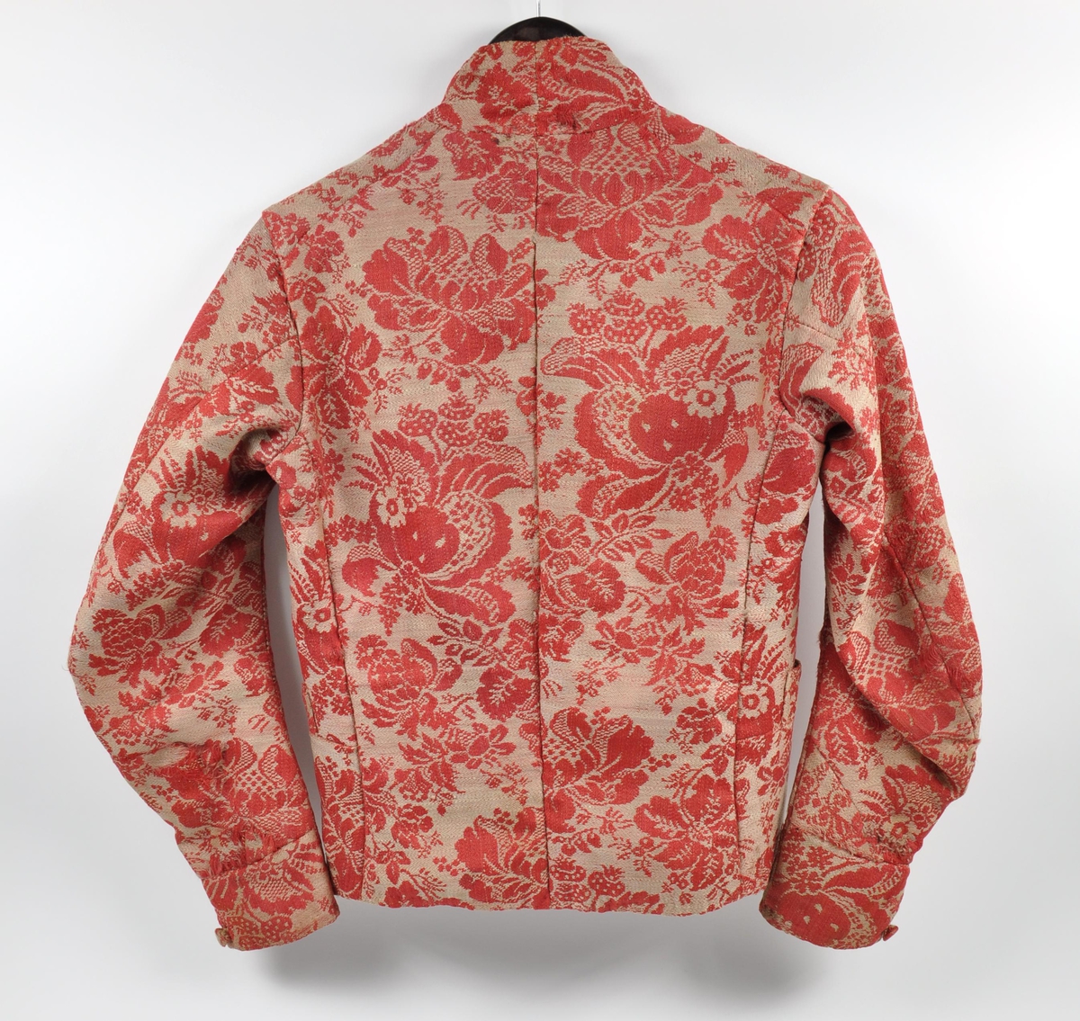 Håndsydd vest av ulldamask, fôret med to typer linstoff. Ryggsømmene er sydd med spilesøm. Vesten har ståkrage, dobbel knapphullrad (18) , trekte knapper (to ulike stoff) (16) - to mangler. Det vil si ni knapphull  og knapper på hvert forstykke. Knapphullene er sydd med lintråd.
To sidelommer. Knapp og knapphull nederst på ermene.