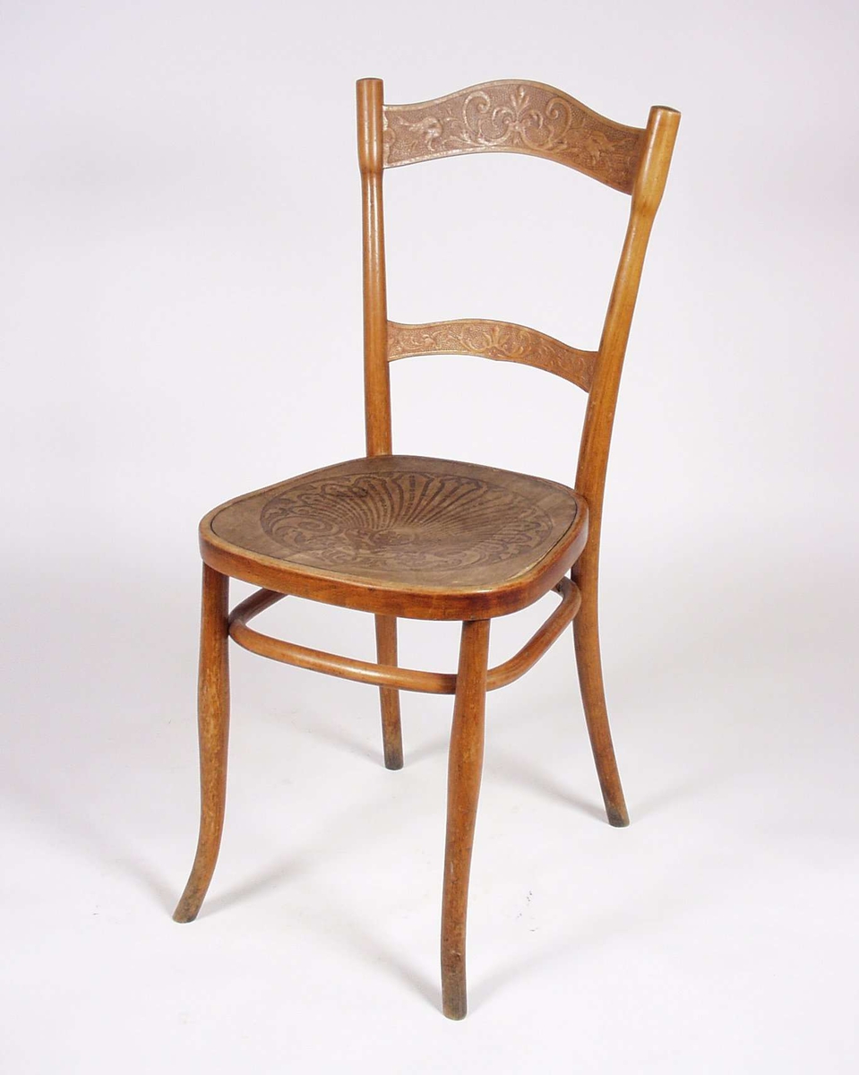 Stolen er av tre med formpresset finer i ryggbrett, tversprosse og sete. Finerplatene har dekor.