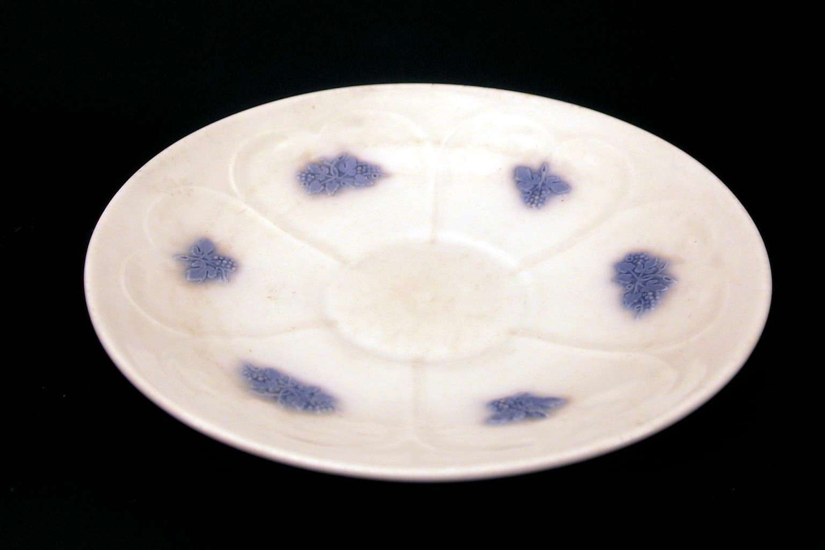 Kaffeskål i hvit porselen med blå relieffdekor. 