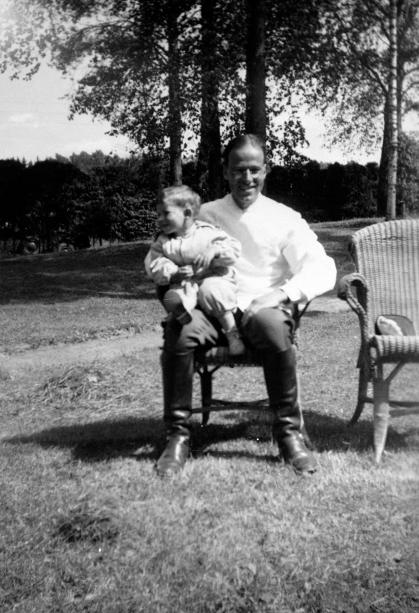 Far og sønn i stol i parken v/Sanitetslegens hus, Gardermoen