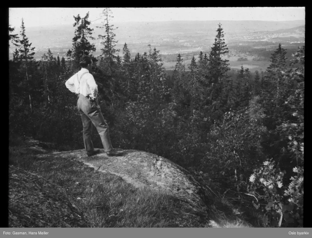 En mann som ser på utsikten fra et berg eller en kolle i skogen