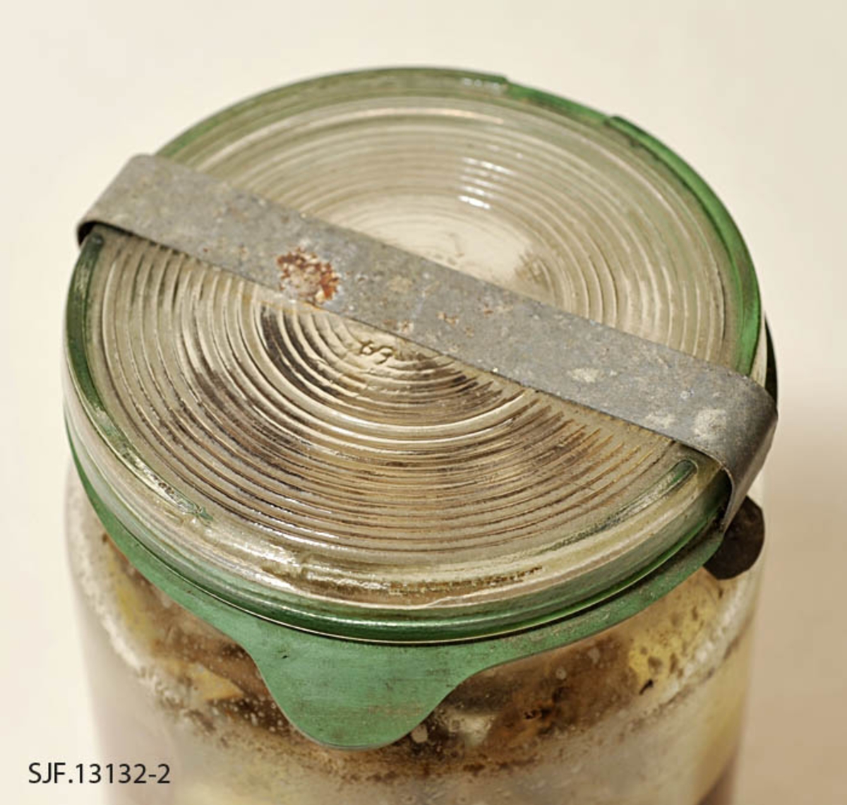 Tiur på hermetiseringsglass, som ble tilbredt i 1958. Glasset består av fire deler: Klar glasskrukke med glasslokket.  Det er en grønn syltestrikk under glasslokk. Dette kan festes med en klemme av metallbit som er flat og avlang. Formen på gjenstanden er sylindrisk. 
