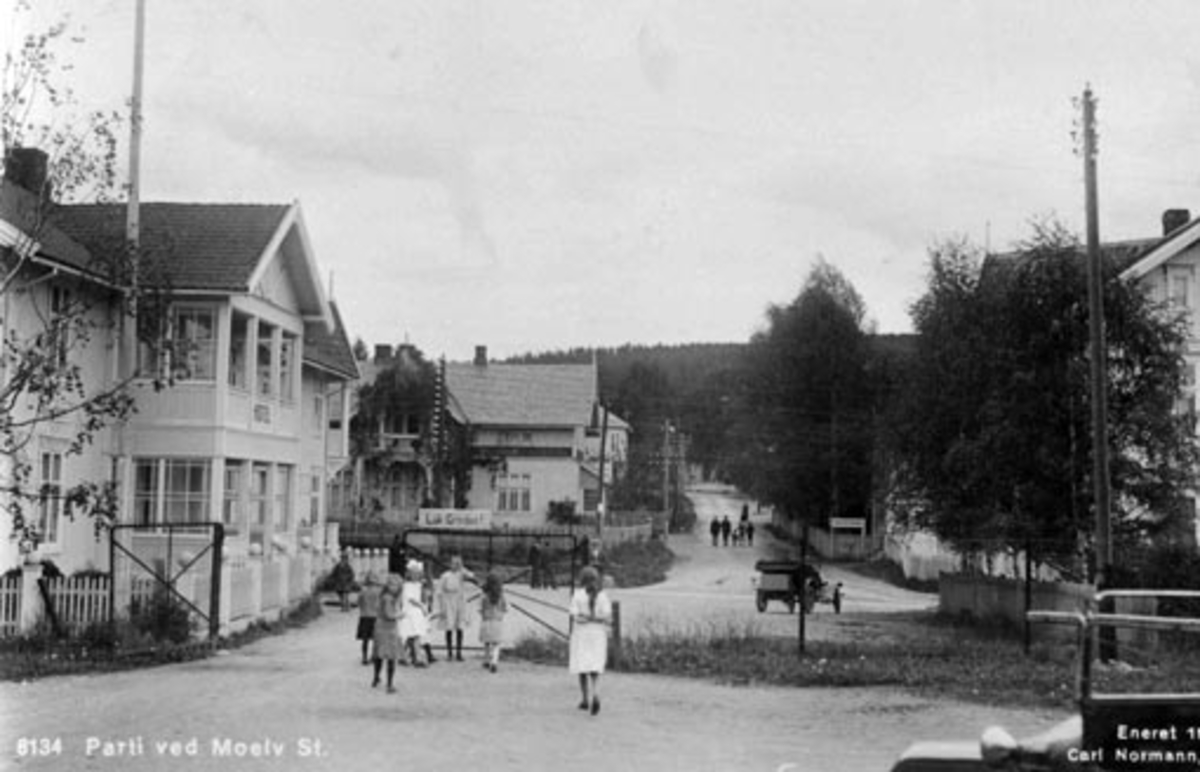 Postkort, Moelv sentrum, sett fra stasjonen mot Åsmarkvegen, til venstre er Moelven hotell, Ringsaker Sparebank, M.P.Dobloug.