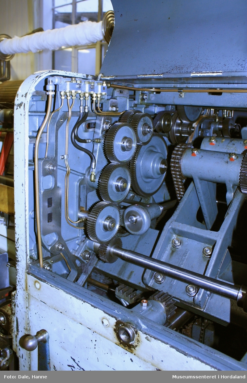 Elektrisk ringspinnemaskin (1958) frå det sveitsiske selskapet Rieter. Øvst på maskina plasserer ein spolane med forgarn frå kardemaskina. Reint teknisk er det tre hovudelement i spinninga:  forgarnet blir strukke, tvista (snodd) for å få meir styrke, før det ferdige garnet blir oppvikla på ein spole eller 'spinnepipe'. Tråden går under eit transporthjul i tre, gjennom støypte løpegangar og vidare nedover: Garnet blir snodd ved at garnet passerer ein løpar som beveger seg på ein ring, før det blir samla på ein sylindrisk metallspole. Det er ei rekkje små støvsugarar langs heile maskina, små røyr som stikk ut over spolane. Desse syg til seg støv og/eller tråden viss den ryk, for å unngå at den kjem inn i maskina. Trådrestar og støv blir samla opp i eit oppsamlingskammer på venstre sida av maskina. Der er det òg ein målar som måler kor mykje maskina spinner.

Drivverket og ein stjernemotor sit på høgre sida av maskina. På sida står det "Rieter" i raudt, og det er to målarar som måler omdreiingar/hastigheit på maskina. Det er ei rekkje med 136 koner på kvar side. Maskina kan byggjast på i seksjonar, og slik utvidast etter behov, noko som er vanleg for spinne- og spolemaskiner.