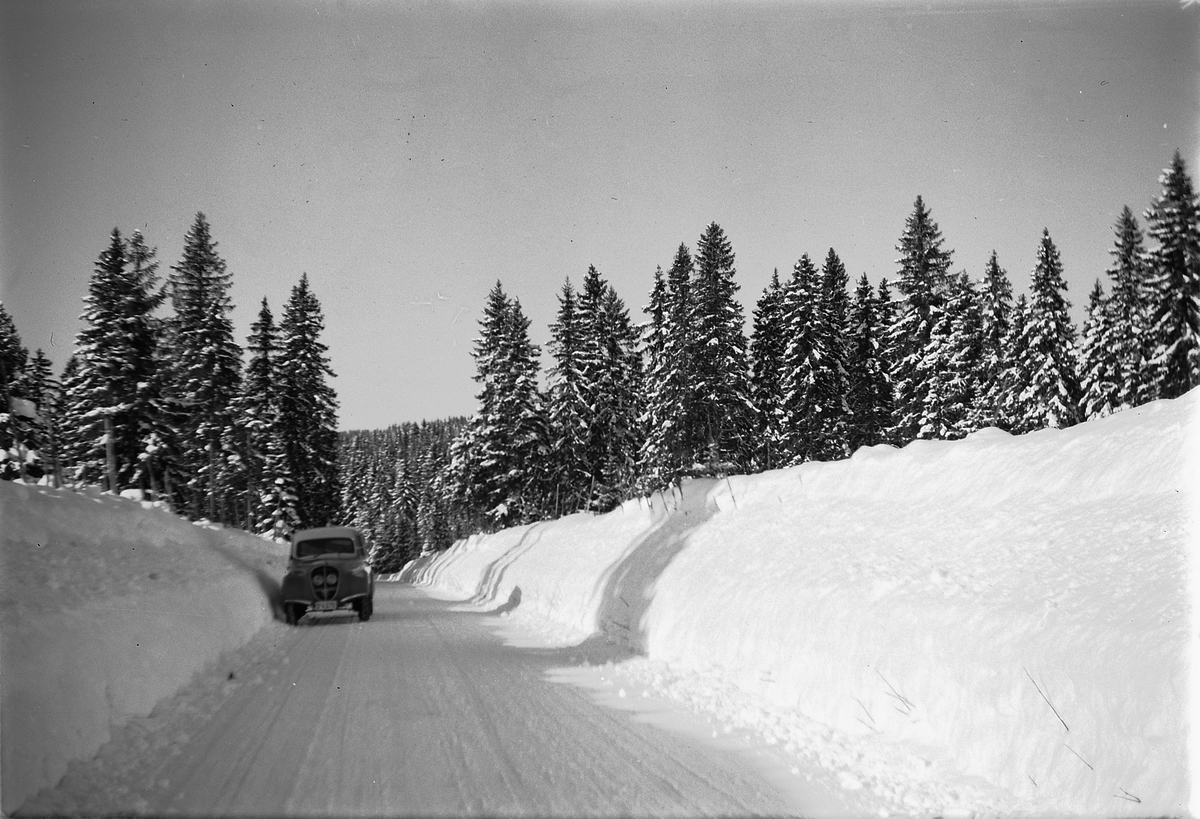Vinterlandskap. Bil på vintervei med brøytekanter. Bilen er en Peugeot reg. nr. D-4376. Snøplogkanter, "snøvinteren" 1951,