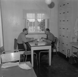 Lademoen brannstasjonen.  Brannmenn ved kjøkkenbordet.