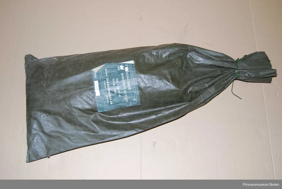 Maskeringsnät i säck av plastväv, materielnummer M1514-005210. Tillverkat 1984 av Diab-Barracuda, Gamleby. Nr 19498.