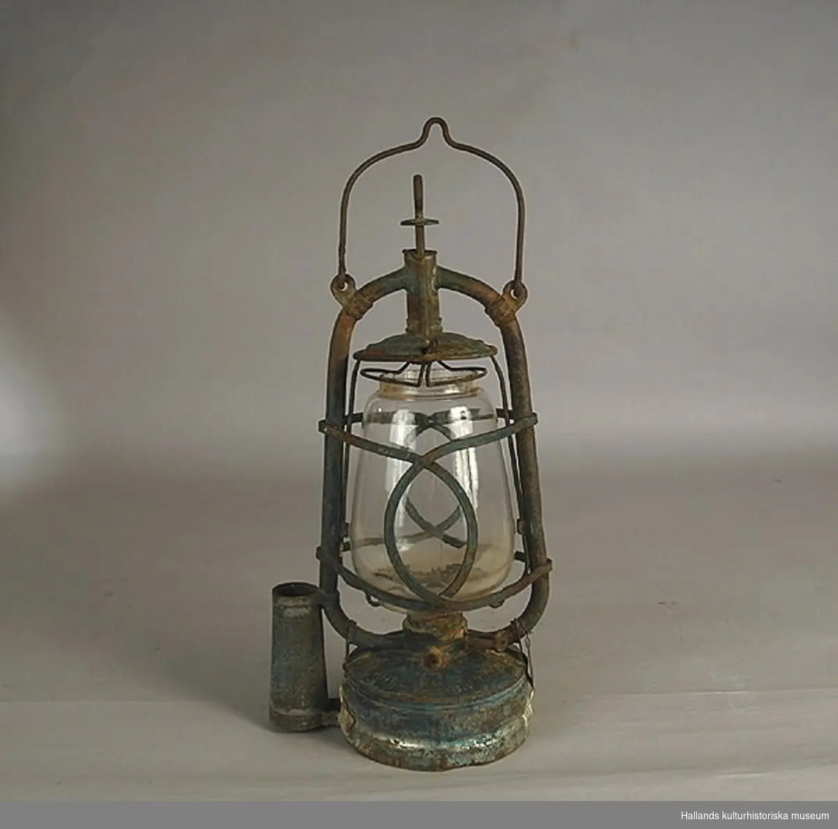 Fotogenlampa (böjlykta) av glas. Hylsan placerad centralt under lyktan. Glas med firmamärke: fladdermus samt O.R.G.M.