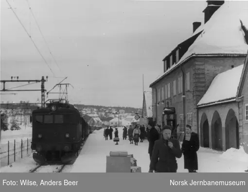 Kongsberg stasjon, persontog trukket av elektrisk lokomotiv El 8 ankommer, reisende på plattformen