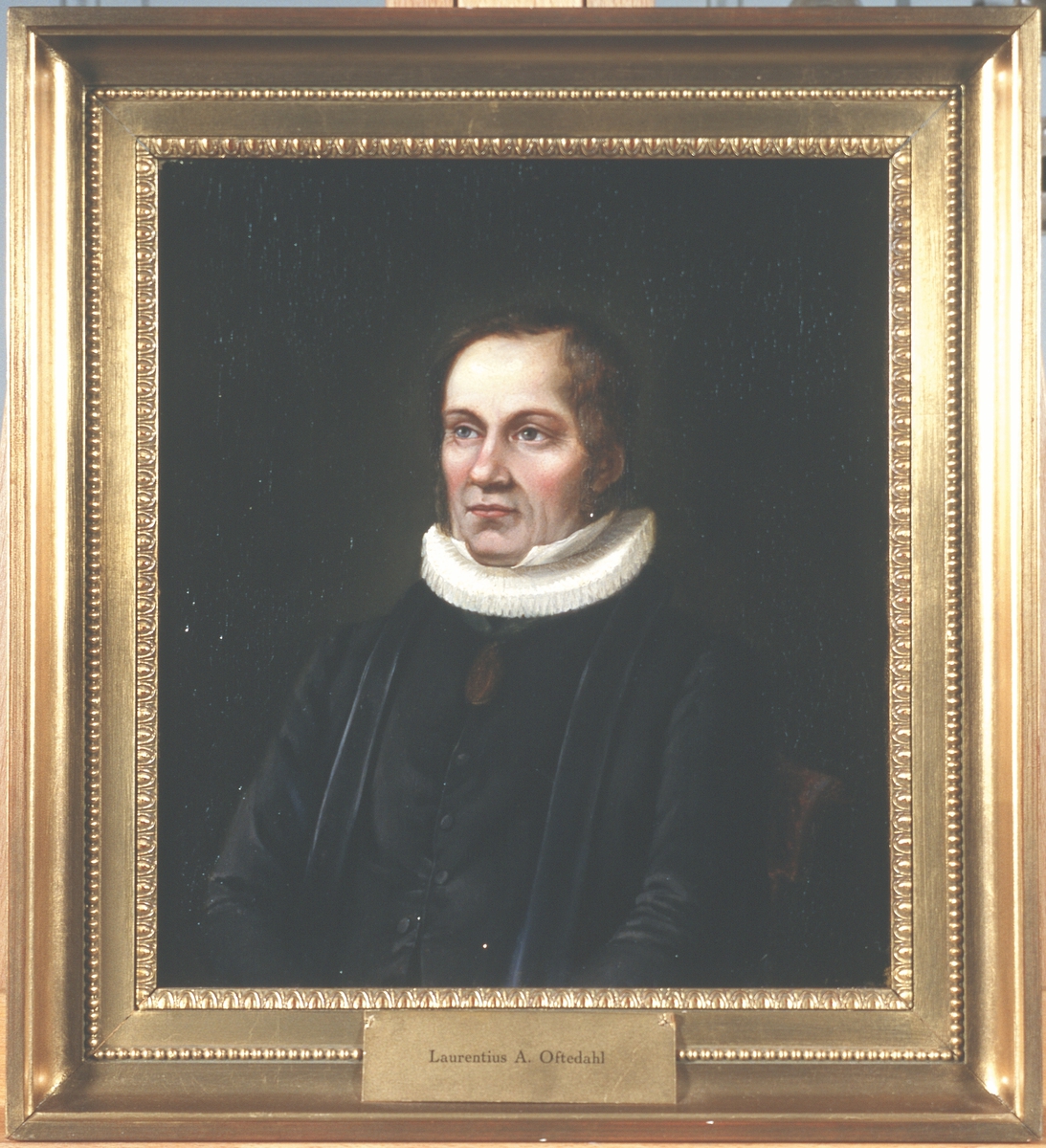 Portrett av Laurentius Oftedal. Prestekjole og -krave. Medalje eller medaljong i bånd rundt halsen.