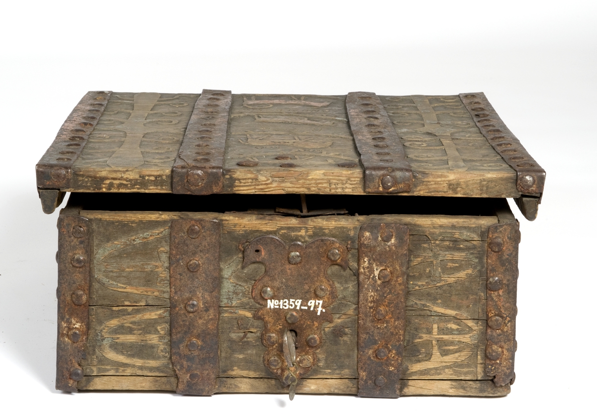 Skrin med flat lokk, jernbeslag og utskåret dekor med plante- og dyrmotiv.