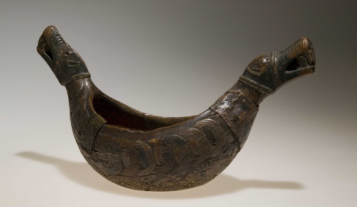 Bolle med håndtak formet som dragehovden. Flatskurd dekor: Geoometrisk bånd. Polykrom maling i flere lag.