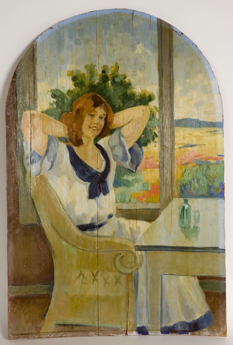 Sittende, hvitkledd kvinne ved bord. Flaske og glass på bordet. Vindusutsikt mot sommerlig hagelandskap.