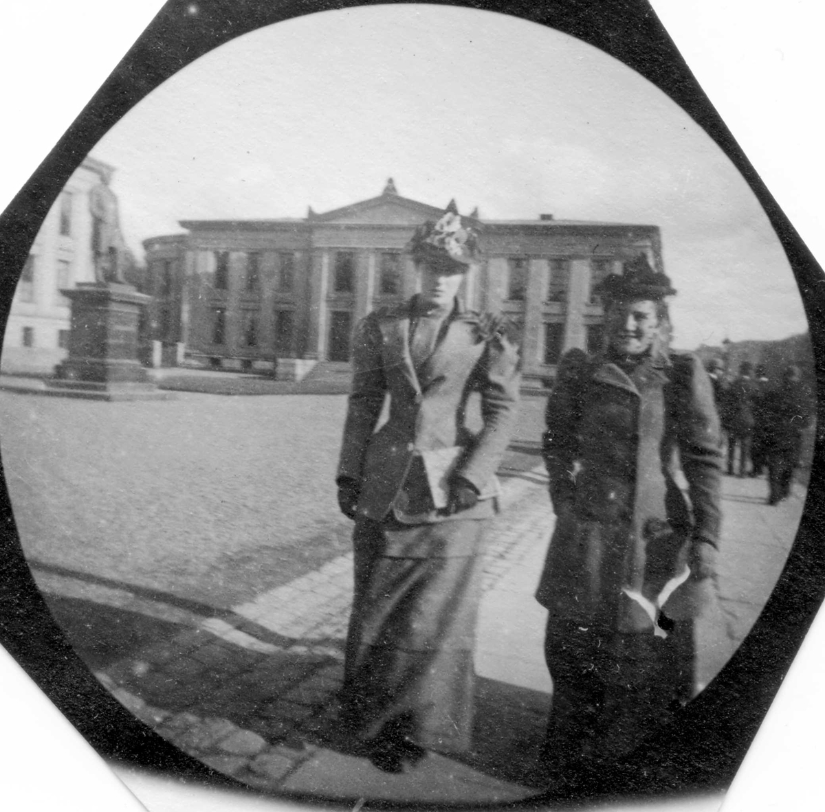 To damer spaserer langs Karl Johans gate, Oslo, ved Universitetsplassen.