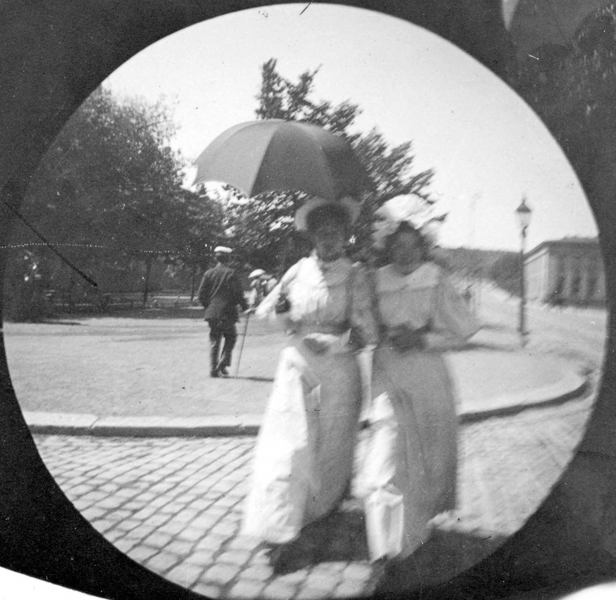 To lyskledde damer spaserer langs Karl Johans gate, Oslo. Universitetet i bakgrunnen.