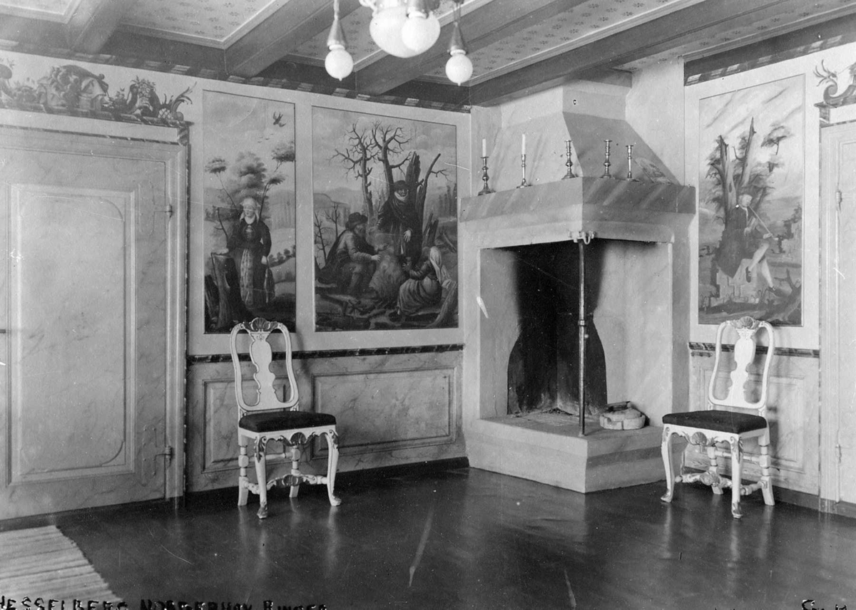 Interiør med to stoler ved en peis på Hesselberg gård. Dekorative veggmalerier malt av Peder Aadnes. Norderhov, Ringeriker, Buskerud.