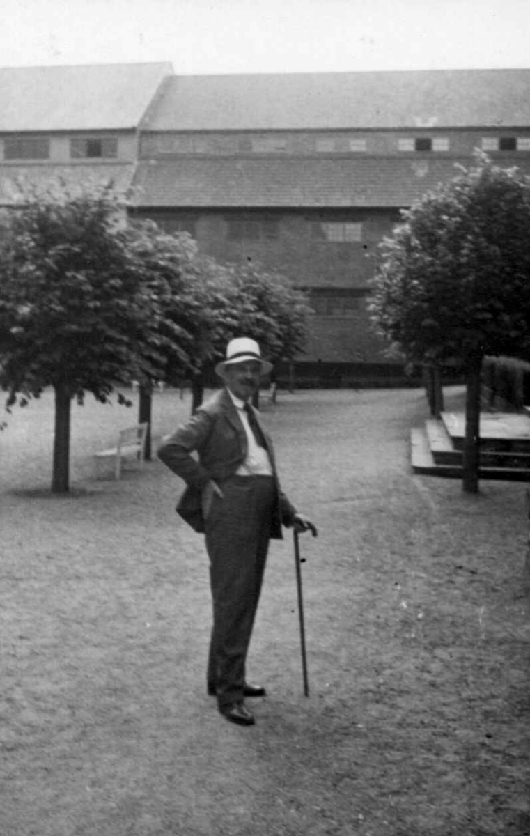 Direktør Hans Aall i Friluftsmuseet i 1934, ikledd hvit hatt og med stokk.
Torget,C-bygg I og C-bygg II i bakgrunnen.